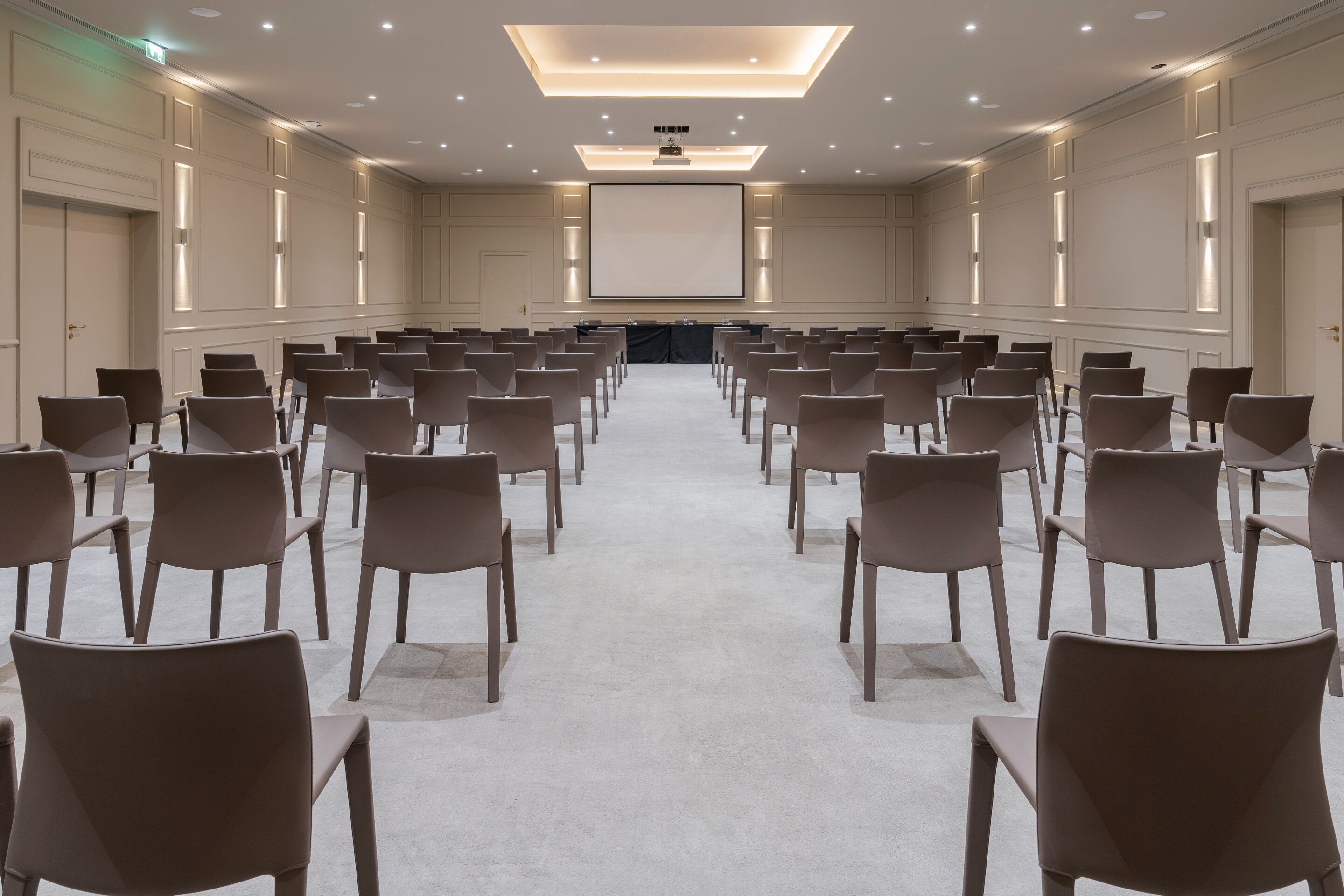 A conference room with rows of chairs facing a large screen at the front.