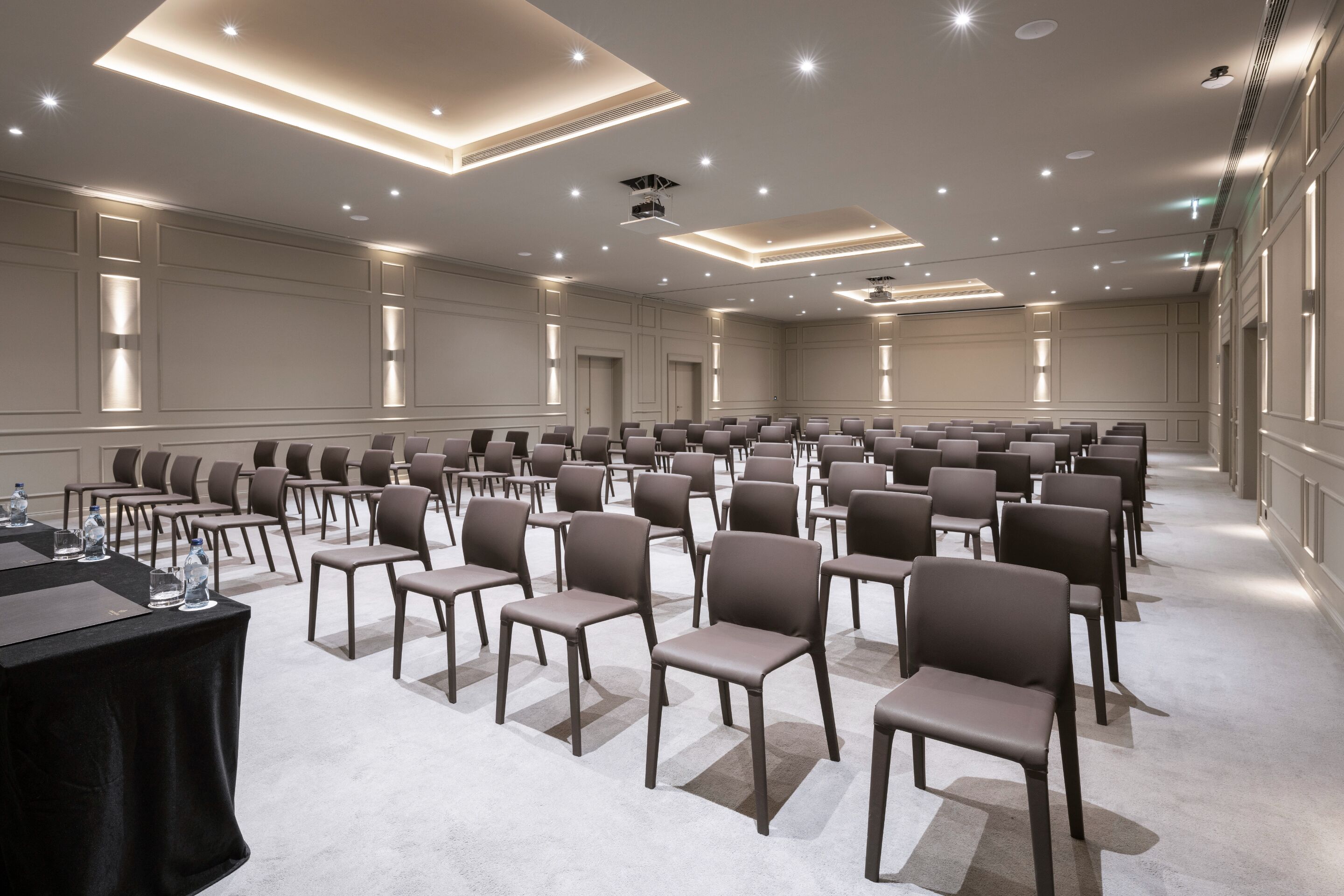 A conference room with rows of chairs, a projector, and a table with water bottles.