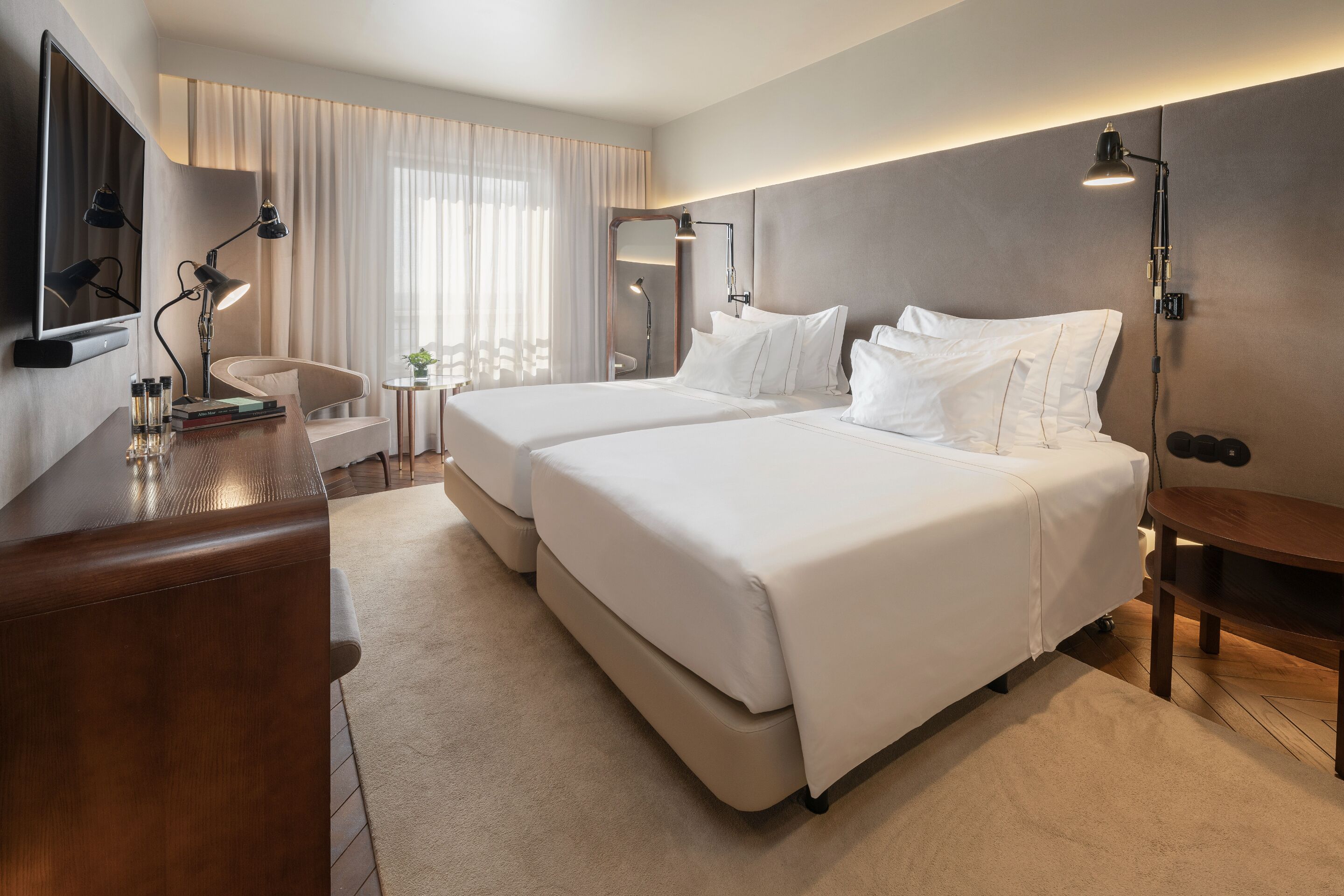 Une chambre d’hôtel avec un grand lit, des tables de chevet, un bureau, une chaise et un téléviseur.
