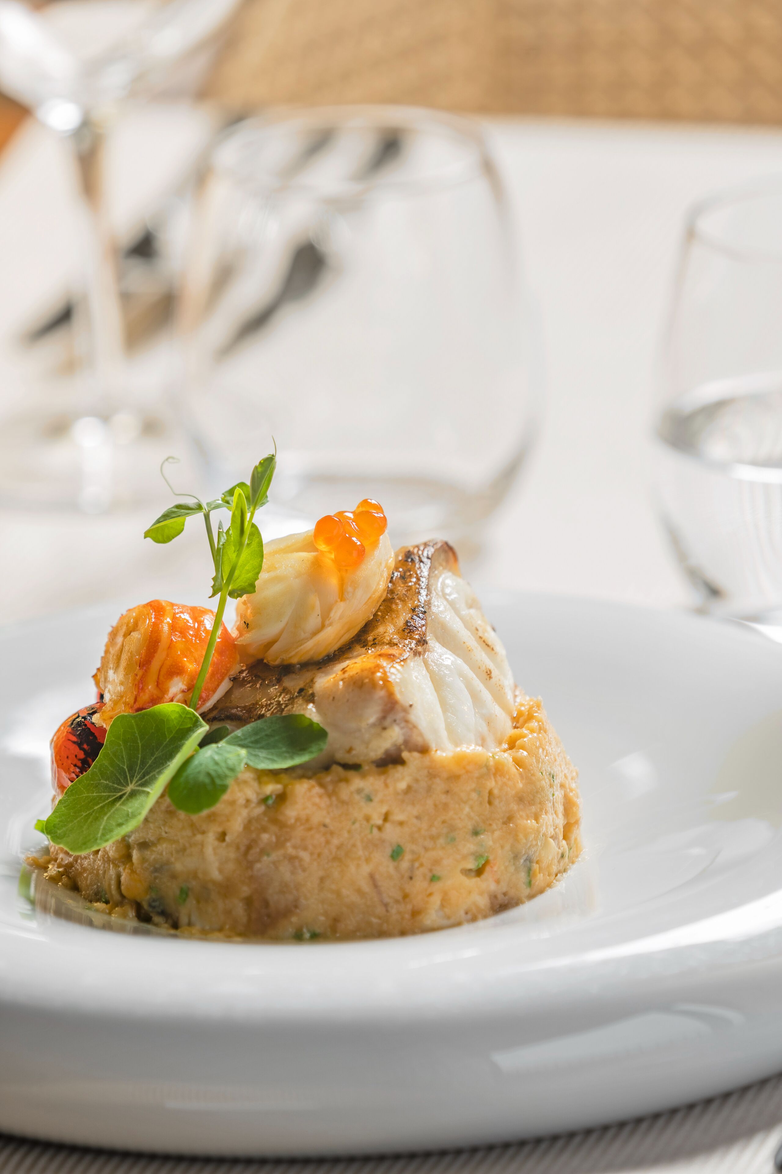 Un plat de fruits de mer servi dans une assiette blanche, avec une fourchette et un couteau à côté.