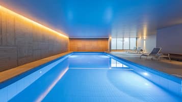 Una piscina techada, sillones reclinables de piscina