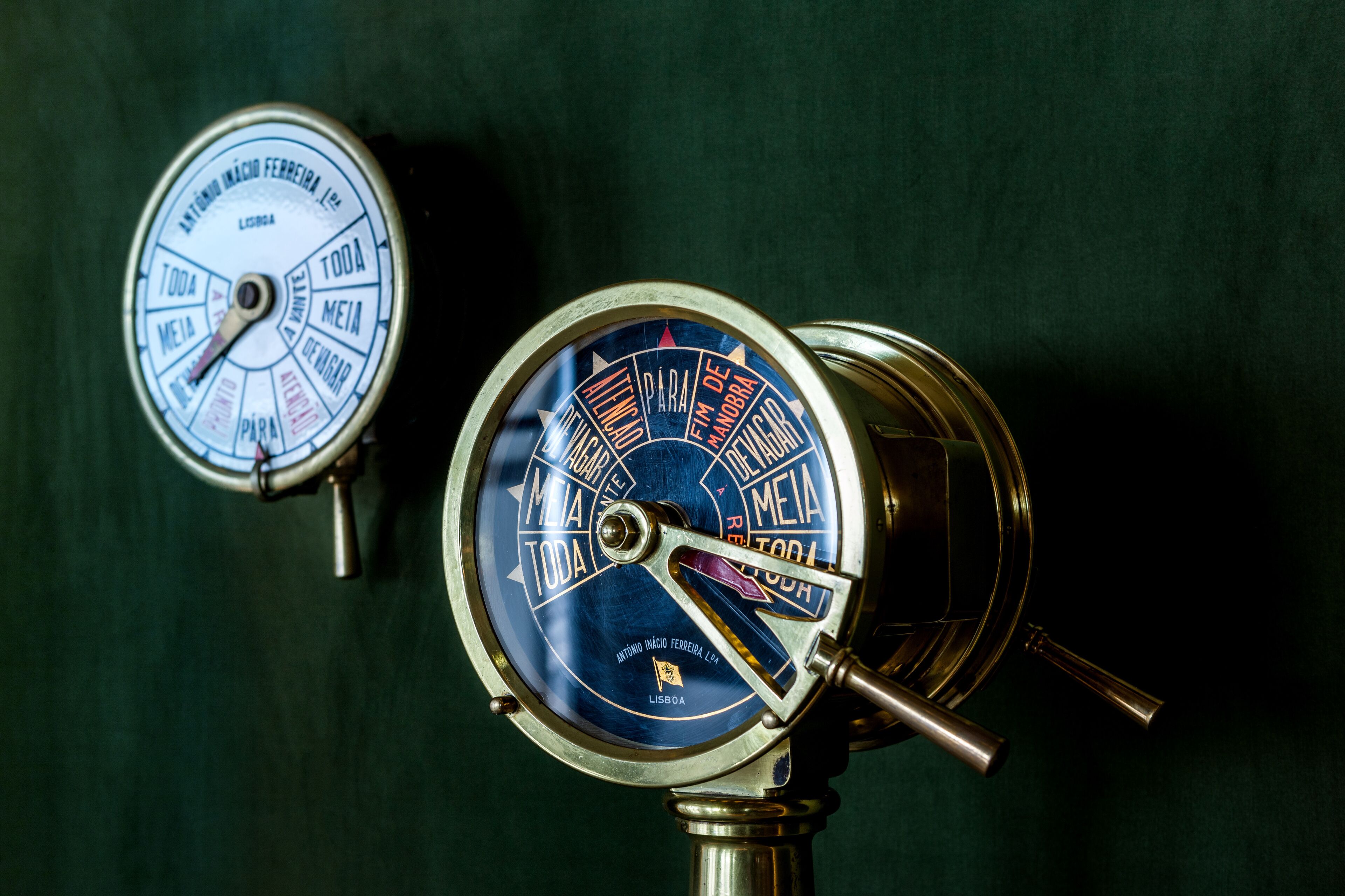 Two nautical depth gauges with labels in Portuguese, mounted on a dark background.