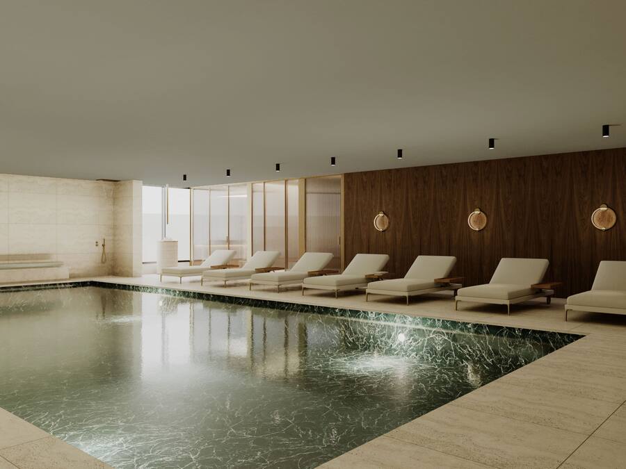 A modern indoor swimming pool with lounge chairs and a wooden wall.