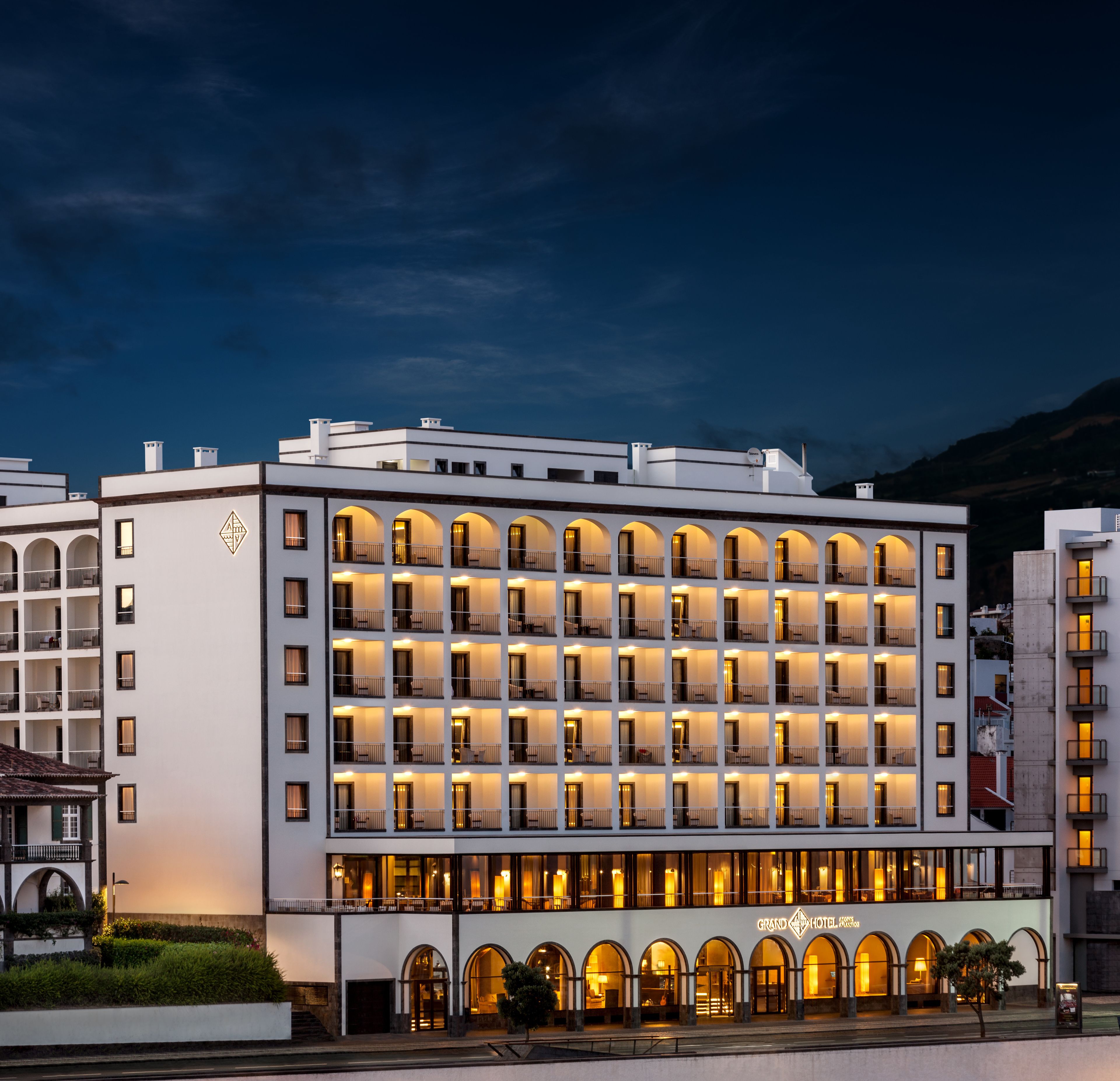 A multi-story hotel with a row of balconies and arched windows.