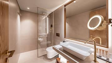 A modern bathroom with a large mirror, a bathtub, and a shower.