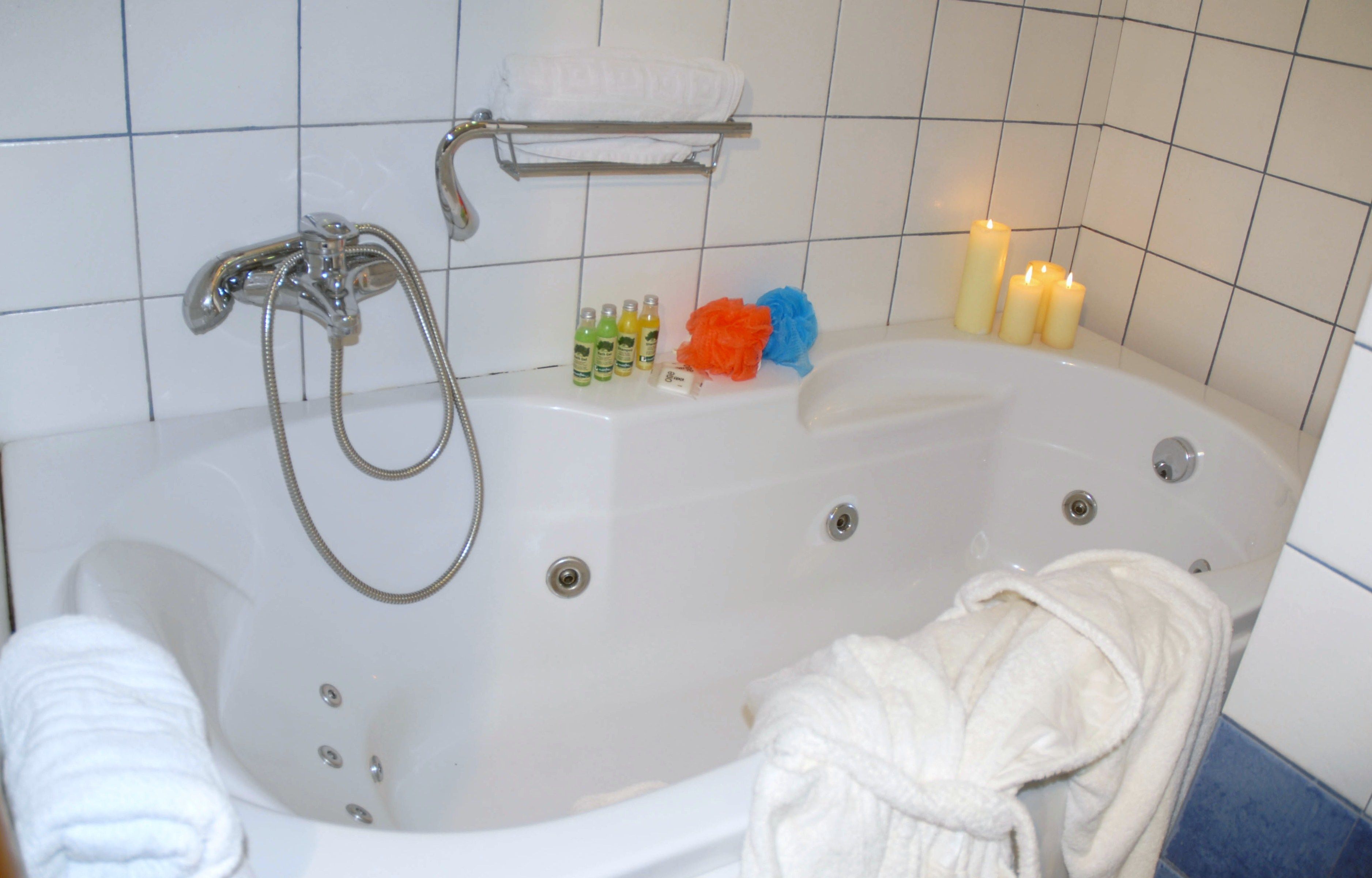 Un baño con bañera, toallero y velas.