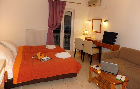 A hotel room with a bed, desk, laptop, and a sofa.