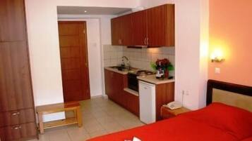A compact hotel room with a kitchenette, a bed, and a small table.