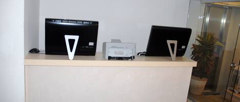 A reception desk with two laptops and a printer.