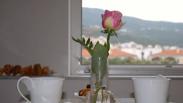 Et bord med en klar glasvase med en enkelt rose, to hvide kopper og en underkop.