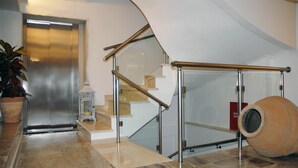 A modern interior with a staircase, a potted plant, and a large vase. - Hotel Aria (Samos)