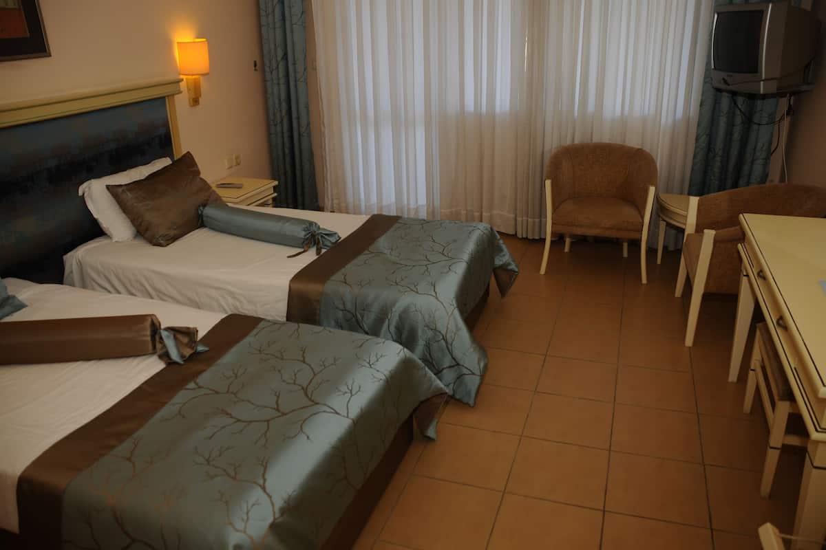 Une chambre d’hôtel avec deux lits, une télévision, une chaise et une table.