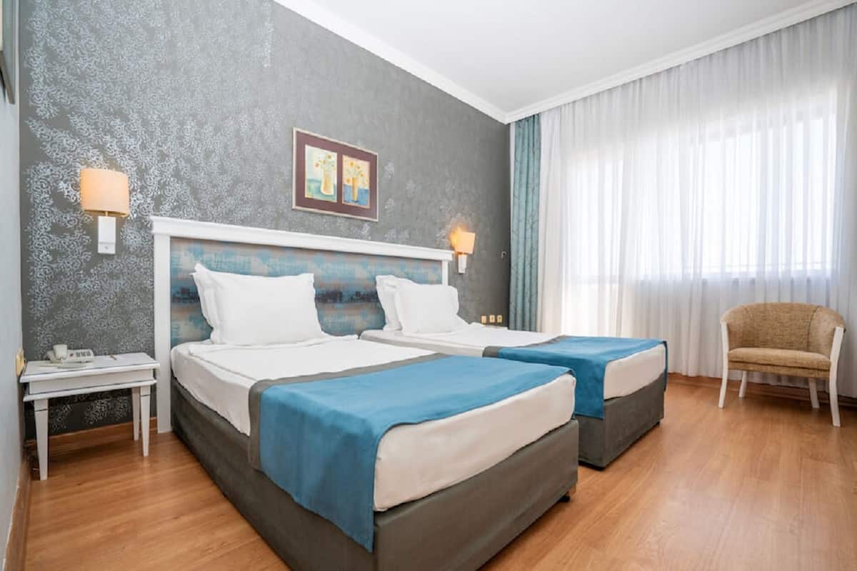 A hotel room with two beds, a desk, and a chair.