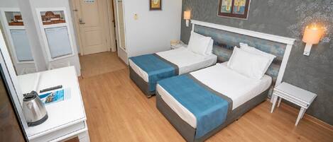 A hotel room with two beds, a desk, a chair, and a small table.