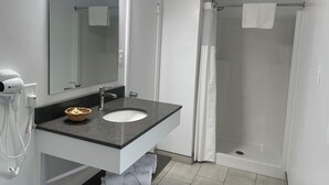 Un baño con lavamanos, espejo y ducha.