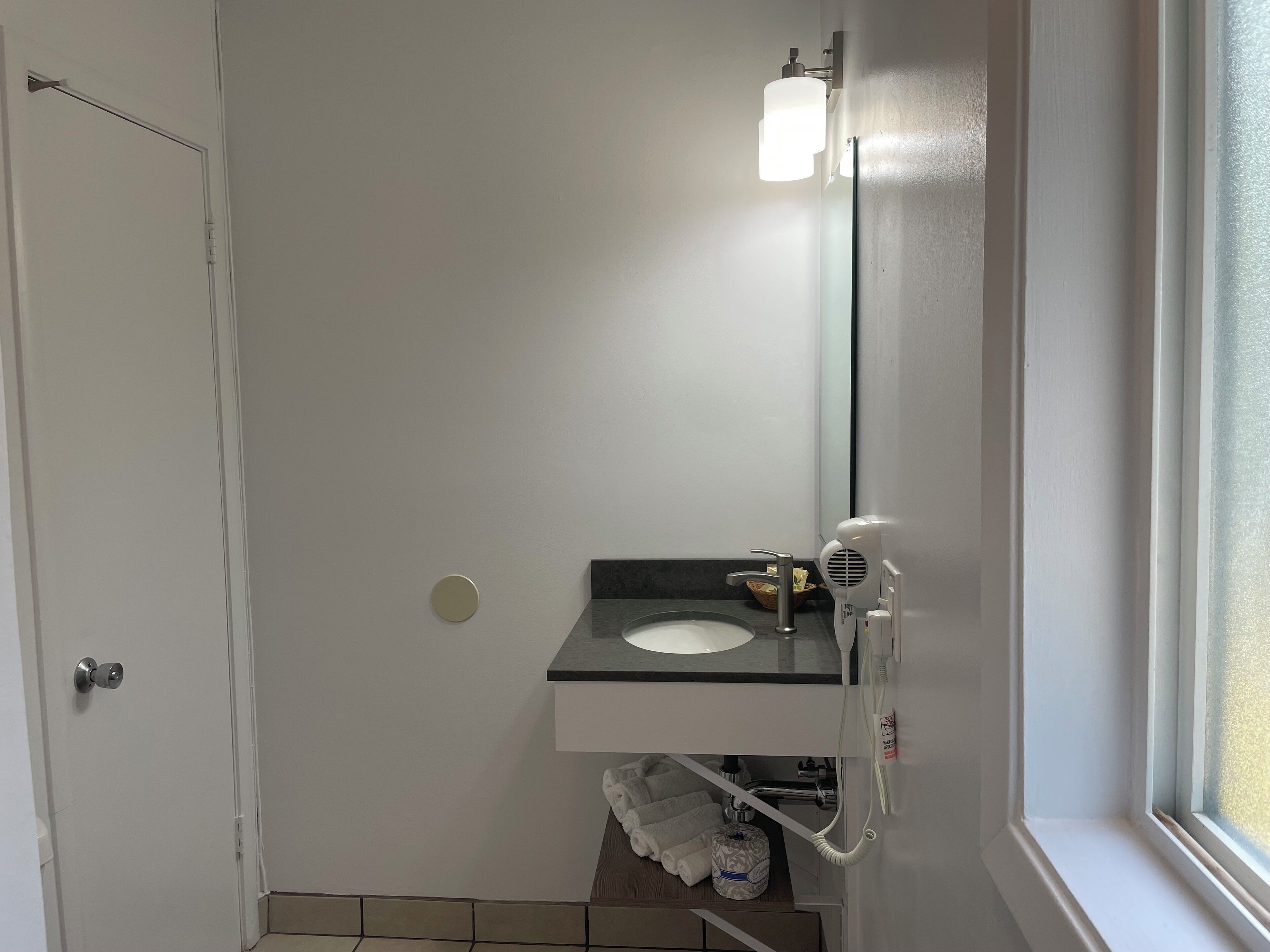 A small bathroom with a white sink, a mirror, and a towel rack.