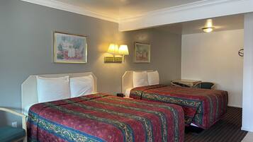 A hotel room with two beds, a desk, a chair, and two wall-mounted lamps.