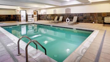 A swimming pool with a tiled deck, a lifeguard chair, and a towel rack.