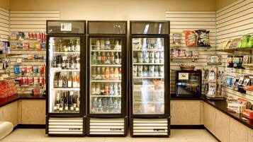 A convenience store with three refrigerated display cases, shelves stocked with snacks, beverages, and other groceries.