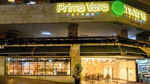 A hotel named "Prima Vera" with a prominent illuminated sign, outdoor seating area, and a visible entrance. - Prima Vera (Jerusalem)