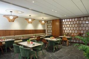 Un restaurante con cabinas y mesas, paneles de madera y lámparas de mimbre colgantes.