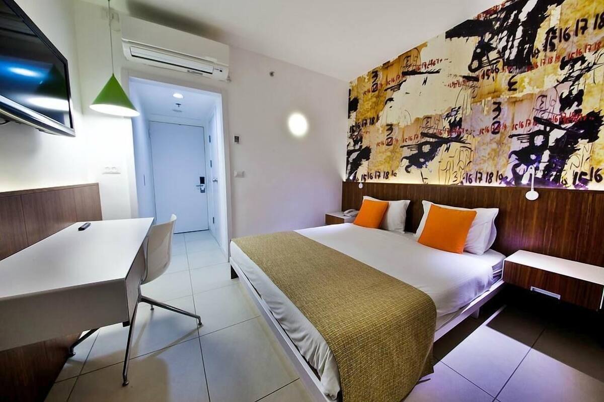 Una habitación de hotel con una cama, un escritorio y un televisor.