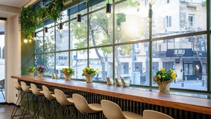 A bar area with a long counter, multiple stools, and potted plants. - Prima Vera (Jerusalem)