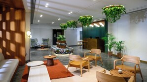 A modern interior with seating arrangements, a reception desk, and hanging plants. - Prima Vera (Jerusalem)