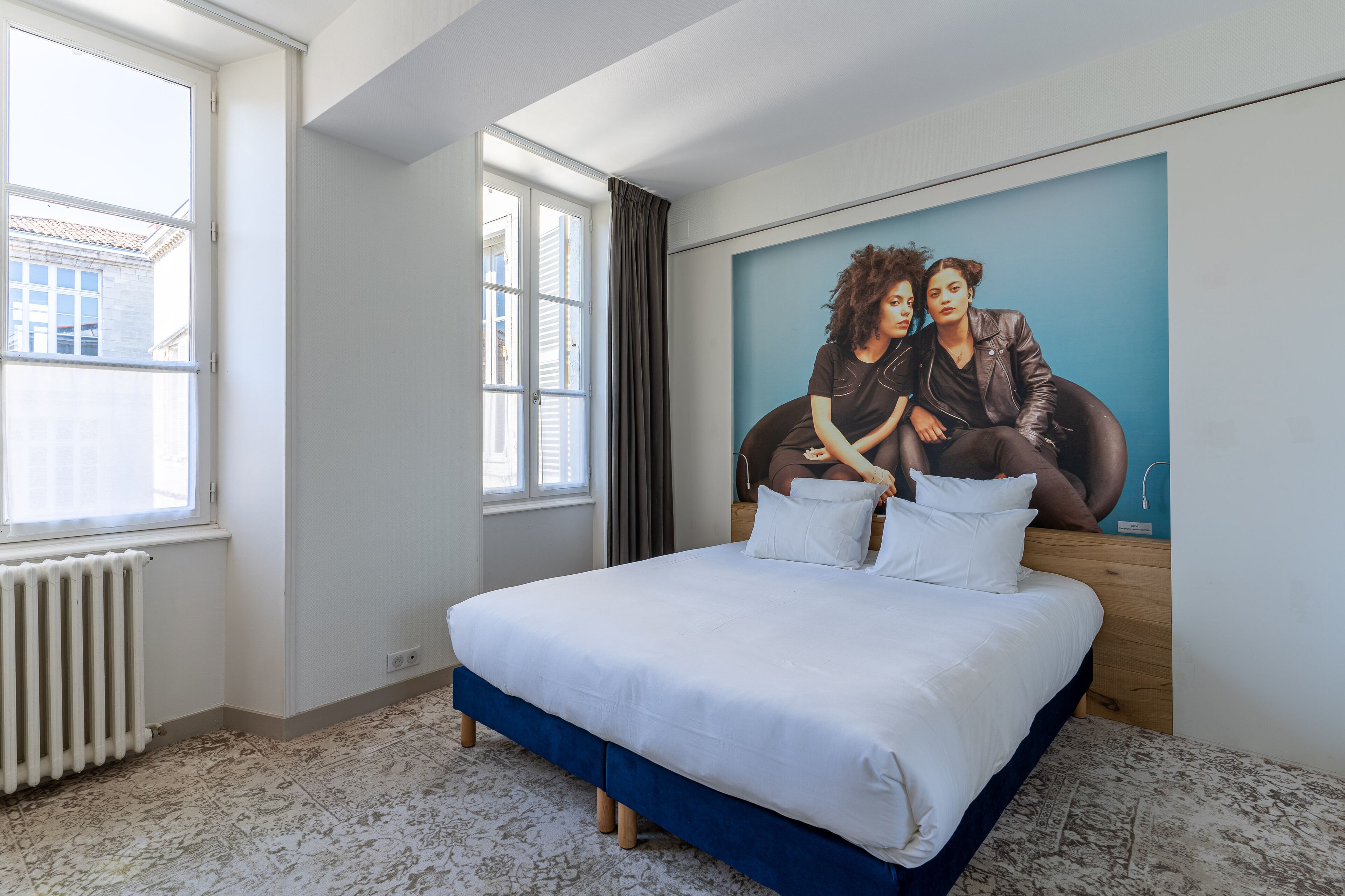 Un dormitorio con una cama grande, una ventana y un mural en la pared.