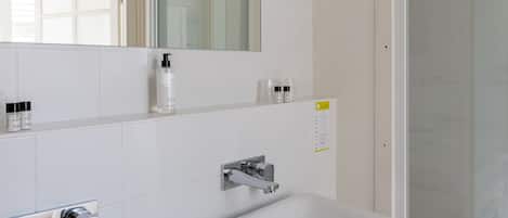 Un baño moderno con dos lavamanos, un espejo y una ducha.