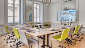 A conference room with a large table, chairs, and a screen displaying a hotel image. - Hotel François 1er Cœur de Ville (La Rochelle)