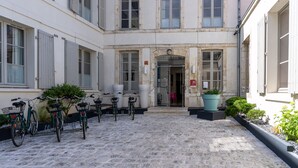 A courtyard with bicycles, a potted plant, and a building entrance. - Hotel François 1er Cœur de Ville (La Rochelle)