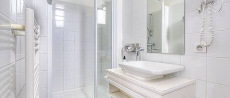 A modern bathroom with a glass-enclosed shower, a white sink, and a hairdryer mounted on the wall.