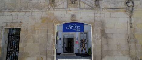 Un bâtiment en pierre avec une enseigne indiquant « HÔTEL FRANCOIS TER » à l’entrée.