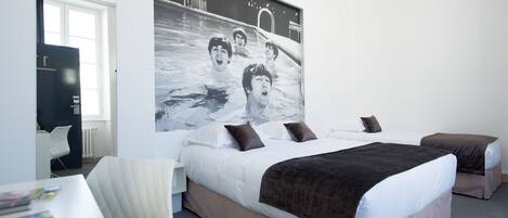 Una habitación de hotel moderna con una cama grande, un escritorio y una obra de arte colgada en la pared.