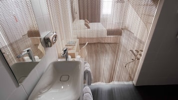 Un baño con lavamanos blanco, un espejo y una cortina de ducha.
