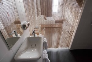 Un baño con lavamanos blanco, un espejo y una cortina de ducha.