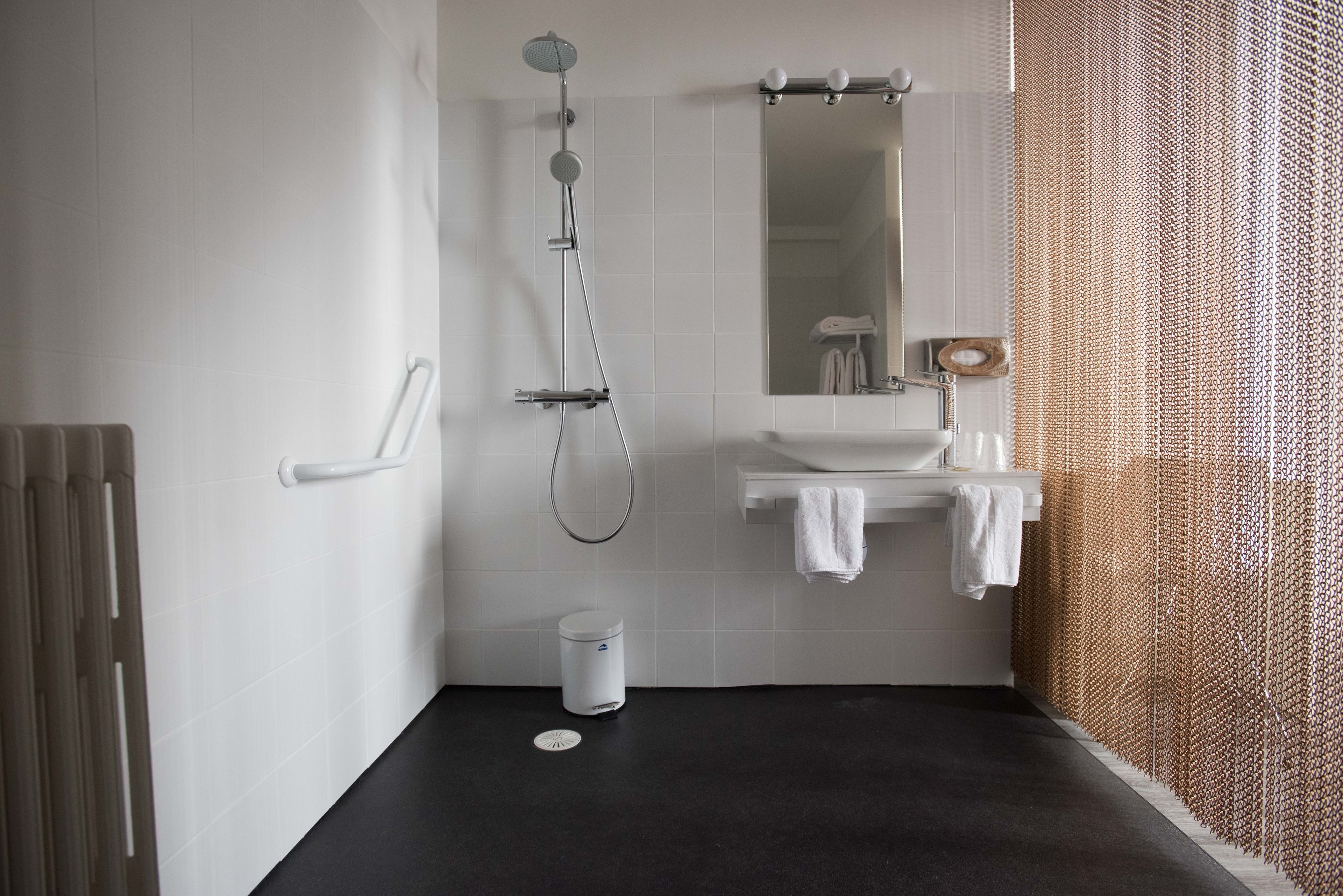 A modern bathroom with a shower, a sink, and a mirror.
