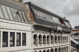 A building with a modern architectural style, featuring a sloped roof with skylights and a series of arched windows.