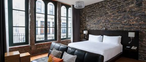 Una habitación de hotel moderna con una cama grande, un sofá de cuero y una pared de piedra.
