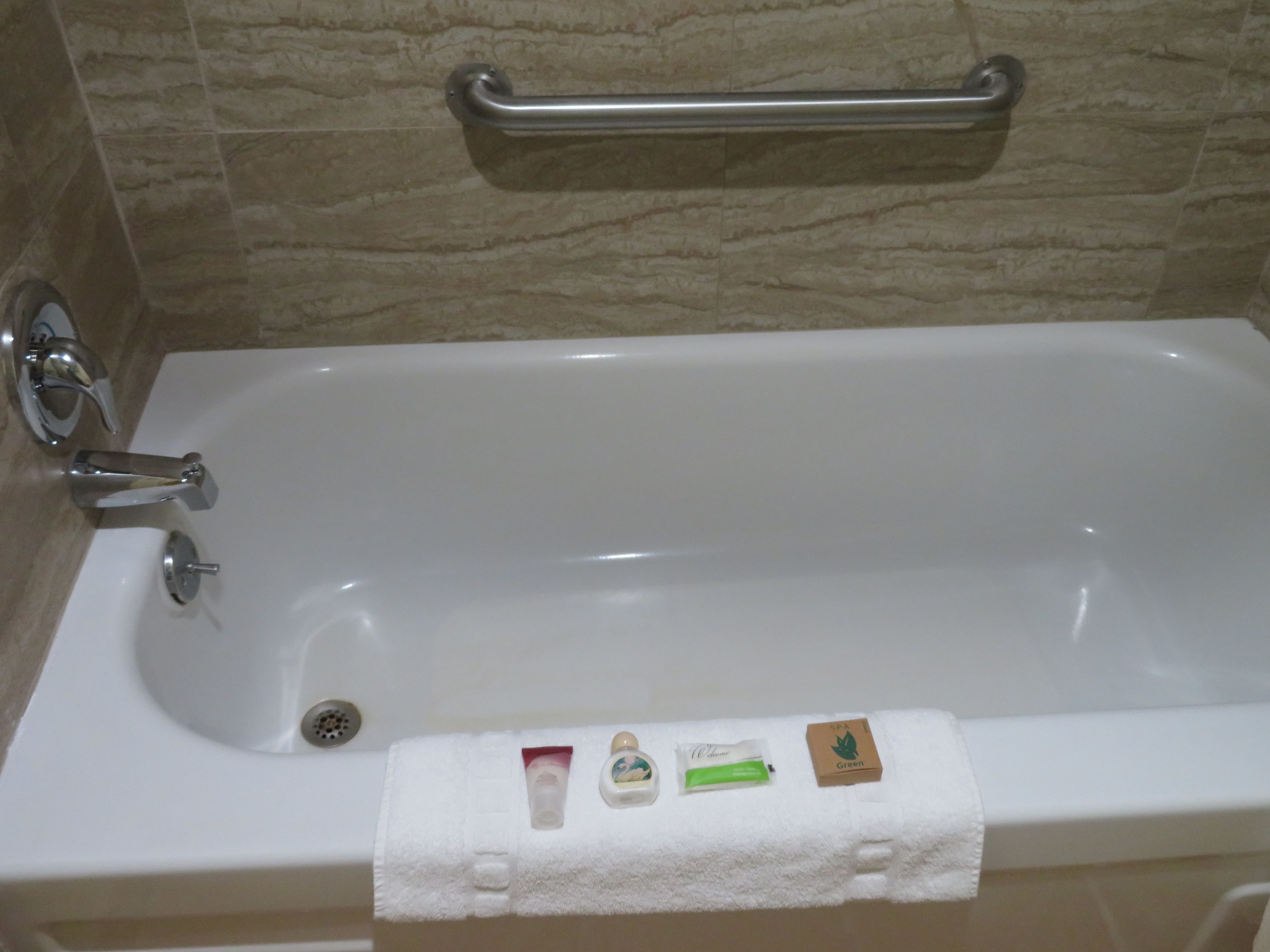Une salle de bain équipée d’une baignoire, d’une barre d’appui et d’un porte-serviettes.