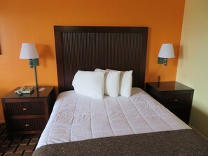 A hotel room with a large bed, two bedside tables, a telephone, and two wall-mounted lamps. - Royal Crest Motel (Medford)