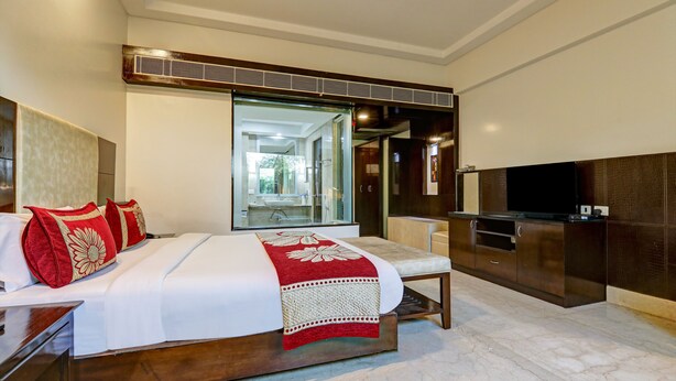 Een moderne hotelkamer met een groot bed, een televisie, een minibar en uitzicht op de badkamer.