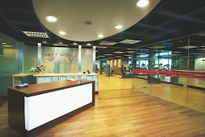 A reception area with a reception desk, a glass wall, and a fitness center visible in the background. - Resorts World Genting - First World Hotel (Genting Highlands)
