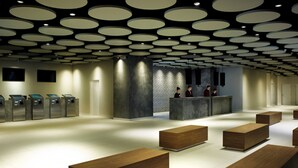 A modern lobby with a circular ceiling design, a reception desk, and wooden benches. - Resorts World Genting - First World Hotel (Genting Highlands)