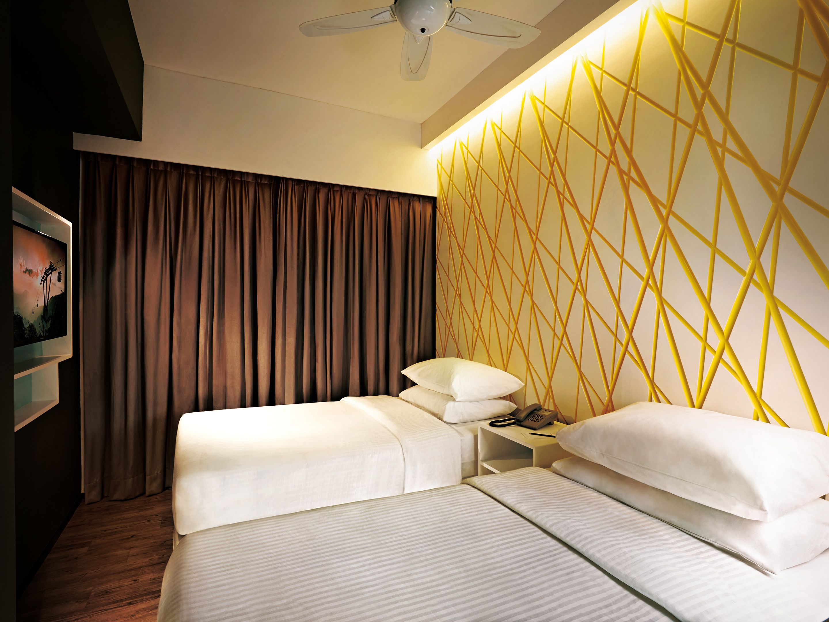 A hotel room with a bed, a nightstand, a telephone, and a wall with a geometric pattern.