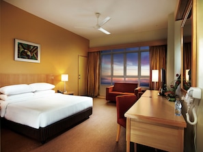 A hotel room with a bed, a desk, a chair, a desk lamp, a telephone, and a window with curtains. - Resorts World Genting - First World Hotel (Genting Highlands)
