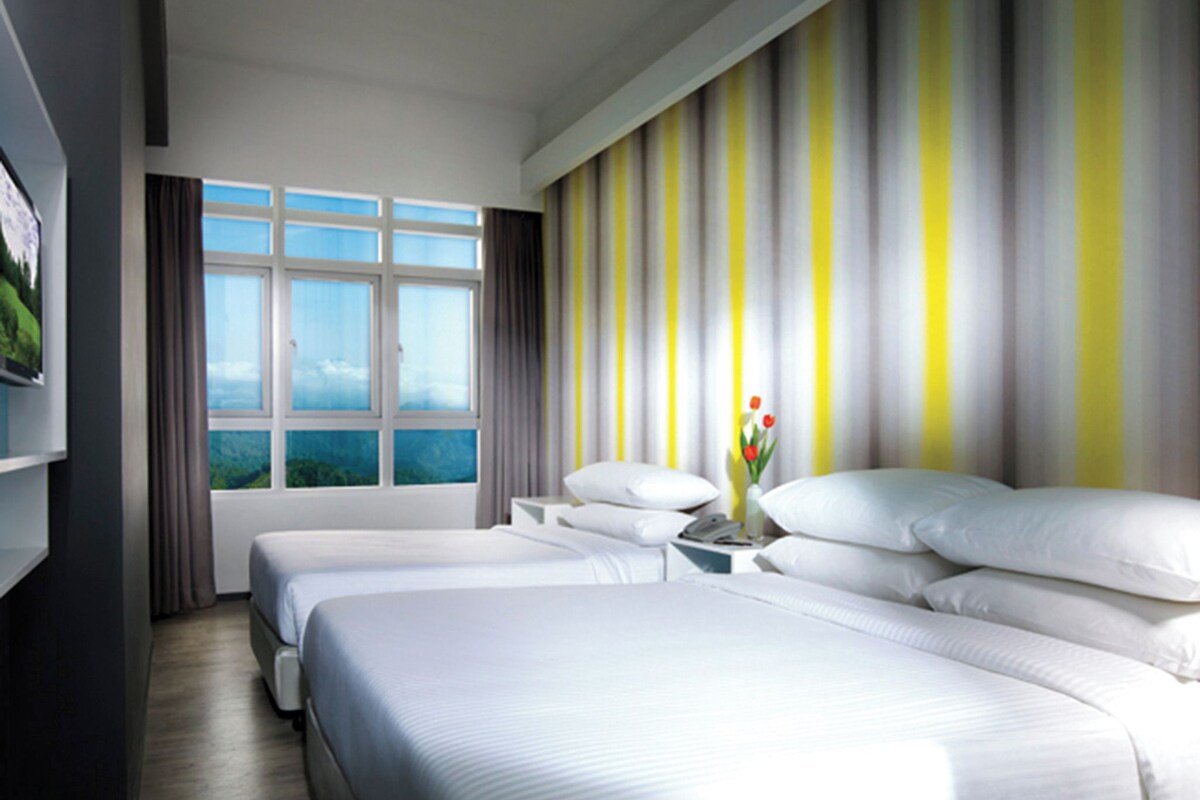 A hotel room with two beds, a large window with a view, a ceiling fan, and a striped wall.