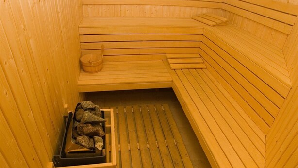 Una sauna con bancos de madera y un asiento.