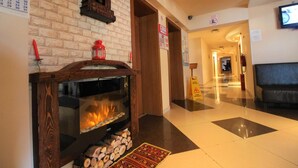 Un hall con chimenea, un reloj, un calendario y un televisor.